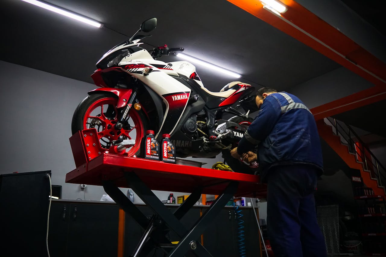 Auto mechanic repairing a Yamaha motorbike in a garage.